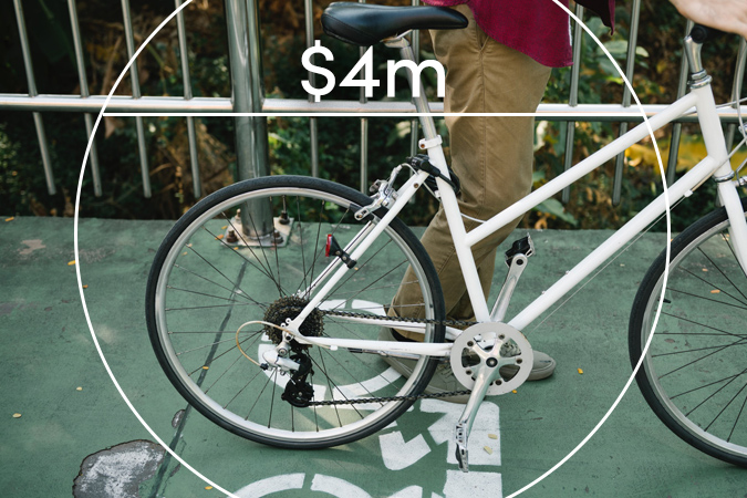 Man walking bicycle with text overlaid: $4m