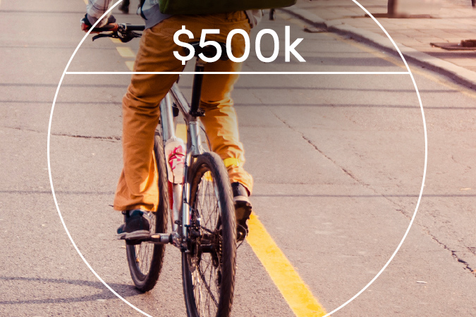 Man with backpack riding bicycle. Text overlaid: $500k