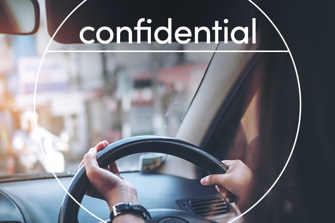 Driver in a car with text overlaid: Confidential