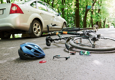 Bicycle on a road with a blue helmet, sunglasses, and a red item scattered nearby; a white car parked in the background.